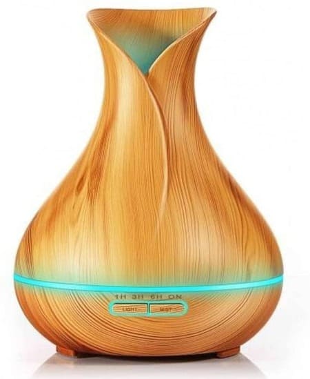 Foto de aromatizador/difusor em forma de garrafa. feito na cor de madeira clara com bico na parte superior na cor azul claro. A foto ilustra o artigo "Aromatizadores elétricos e sua incrível popularidade" do site Ori Mystyco.
