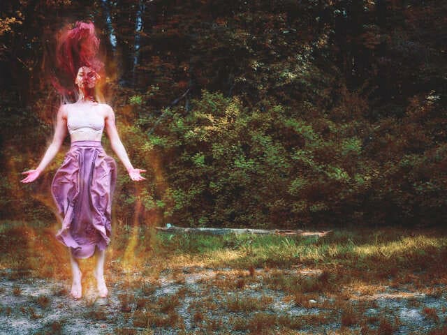 Imagem de uma mulher em pé no meio de uma floresta. Em volta da mulher pode-se ver uma luz dourada representando a energia del. A foto ilustra o artigo "O Neoxamanismo e o auge do xamanismo psicodélico" do site Ori Mystyco.