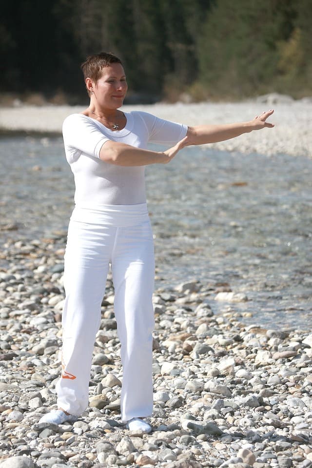 Foto de mulher com roupa branca praticando Shi Kung ou Qi gong na praia. A imagem ilustra o artigo 10 benefícios do Chi Kung em sua vida do site Ori Mystyco.