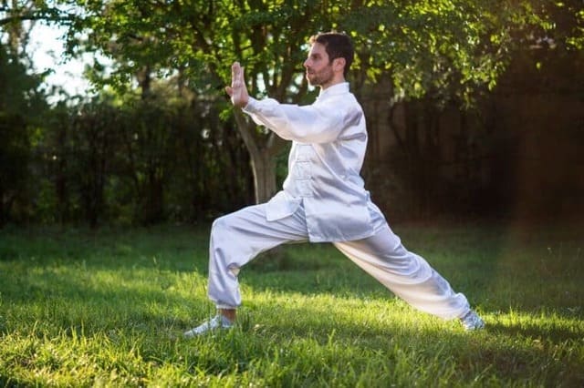 Foto de home com roupa branca praticando Chi Kung ou Qigong no jardim. A imagem ilustra o artigo 10 benefícios do Qikong em sua vida do site Ori Mystyco.