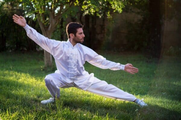 Fot de Homem com roupa branca praticando Chi Kung no jardim. A foto ilustra o artigo Chi Kung: O que é? Origem e suas aplicações do site Ori Mystyco.