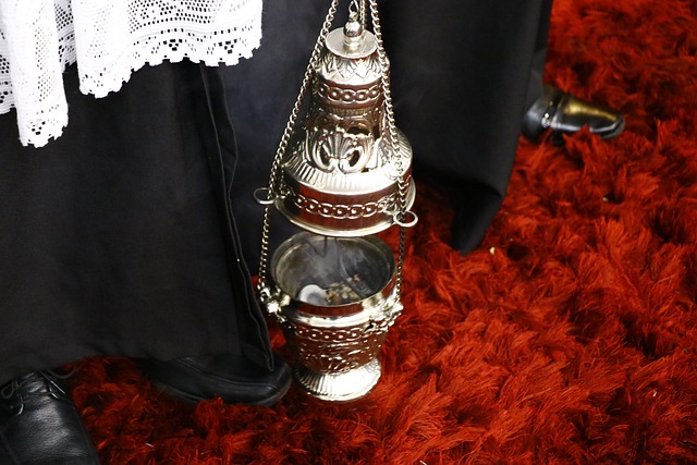 Foto mostra uma batina preta e estola branca de renda branca de um padre com um turíbulo, ou defumador, prateado. A foto ilustra o artigo Ritual de Limpeza: Como fazer o seu? do site Ori Mystyco