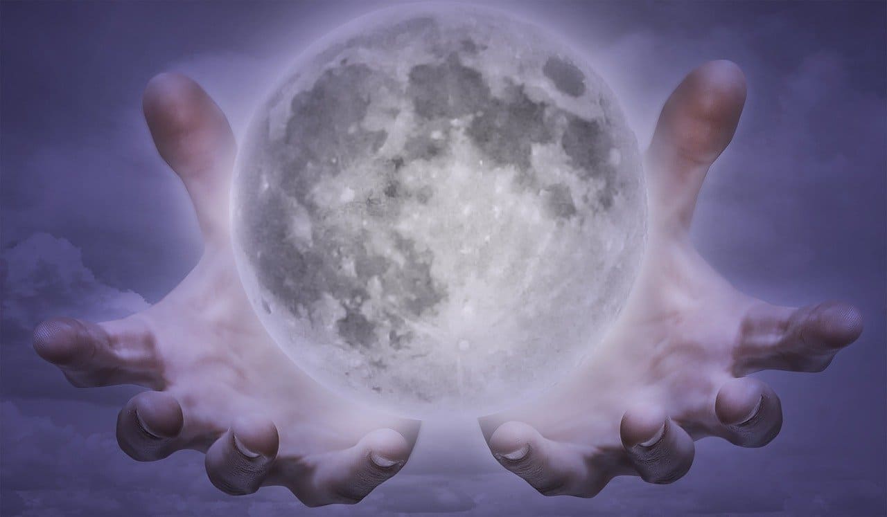 Imagem de mãos juntas com palma para cima e mundo sobre elas. Das mãos saem campos enegéticos. A imagem serve para ilustrar o artigo O que é Reiki à distância? Quando e como aplicá-lo? para o site Ori Mystyco