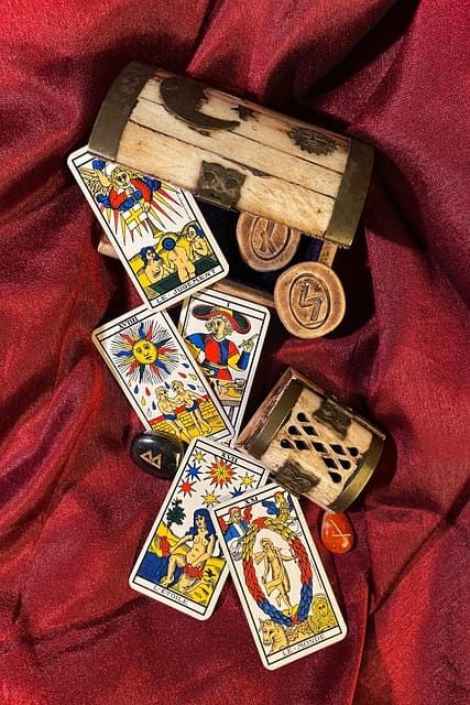 Foto de cartas do Tarot de Marselha sobre uma mesa esotérica com runas de pedra e runas de madeira para ilustrar a página que contém a tirada de Tarot Sim ou Não - Tarot de Marselha do site Ori Mystyco.