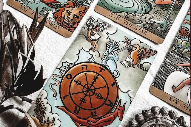 foto das cartas do tarot a Roda da Fortuna, A Estrela e e o Mundo sobre uma mesa. A foto ilustra a página Sobre o Ori Mystyco do site Ori Mystyco.